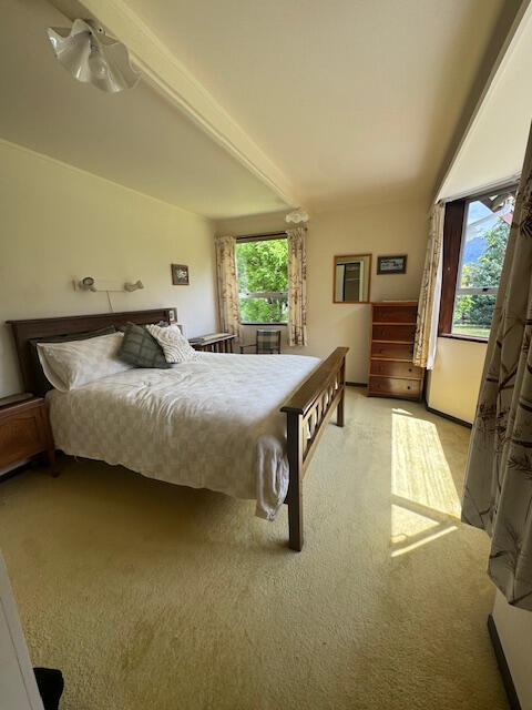 Decluttering · interior & exterior Styling · Property Staging Bright bedroom with a double bed, white walls, wooden floor, and a garden-view window